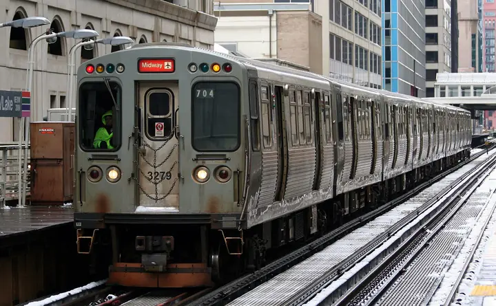 A CTA 'L' train on the elevated tracks of the Loop, between downtown buildings.