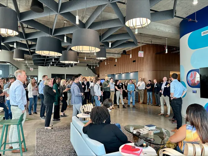 Portal members and guests gathered in conversation in the common area beneath large pendant lamps.