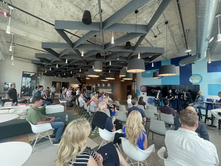 An audience in white chairs listening to a panel in Portal's town hall space.