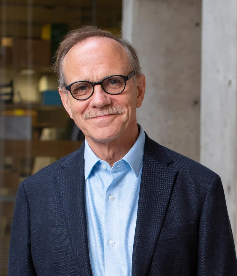 Portrait of Dr. Rusty Gage in a navy suit and light blue shirt, smiling, outdoors at the Salk Institute.